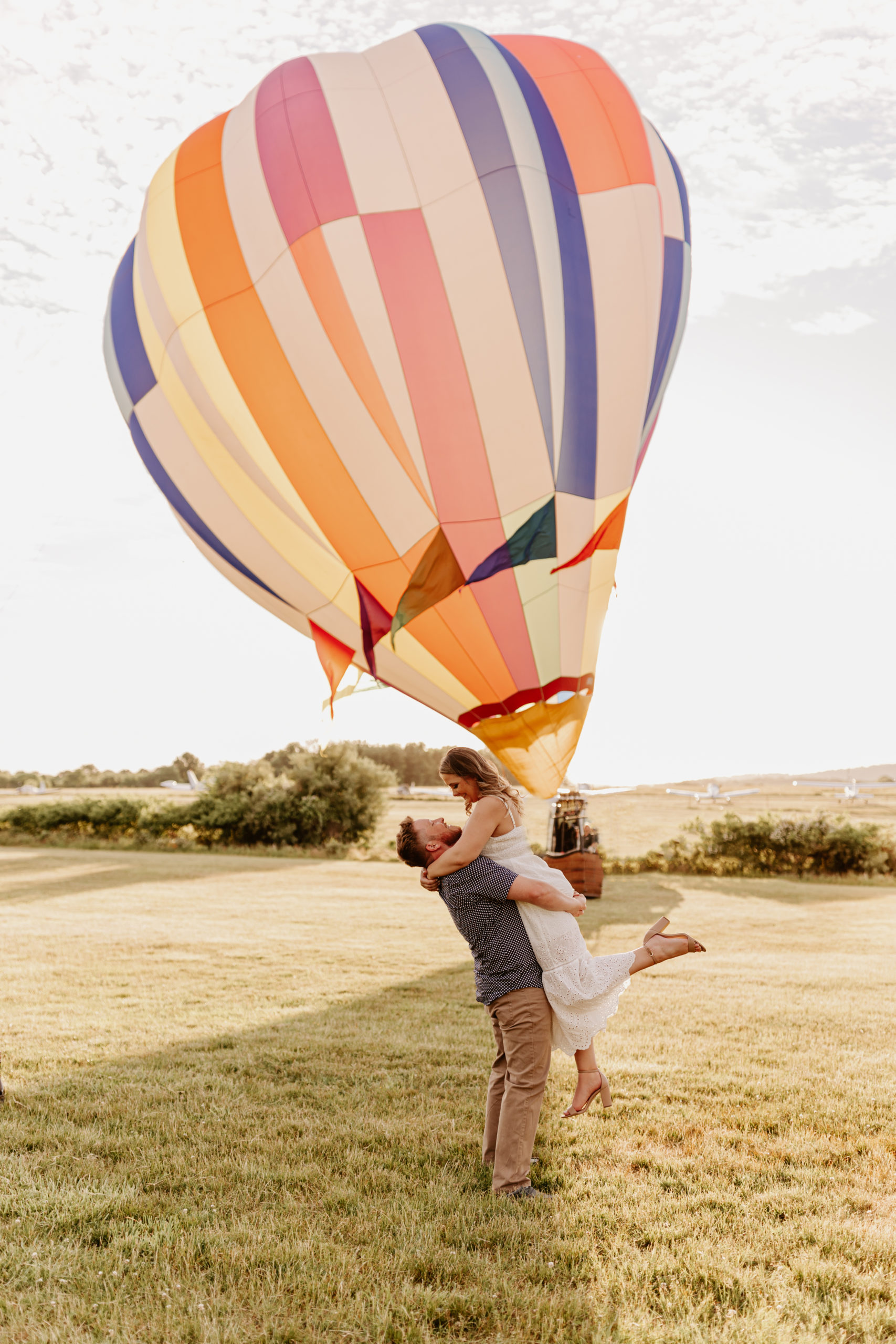 Couple hugging in front of a hot air balloon at engagement session in NJ